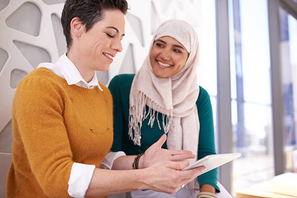 Brainstorming their way to better business Shot of two colleagues using a digital tablet together in a modern officehttp://195.154.178.81/DATA/i_collage/pu/shoots/806247.jpg hijab stock pictures, royalty-free photos & images