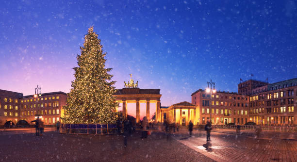 brandenburger tor in berlijn met kerstboom en dalende sneeuw in de avond - berlin snow stockfoto's en -beelden