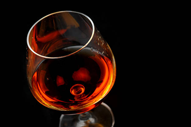 brandy in glass snifter of  brandy in  elegant  glass.  black background calvados stock pictures, royalty-free photos & images