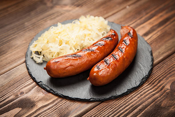 bratwurst und sauerkraut auf holztisch - bratwurst stock-fotos und bilder
