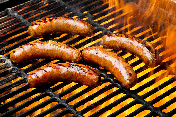 bratwurst or hot dogs on grill with flames - korv bildbanksfoton och bilder