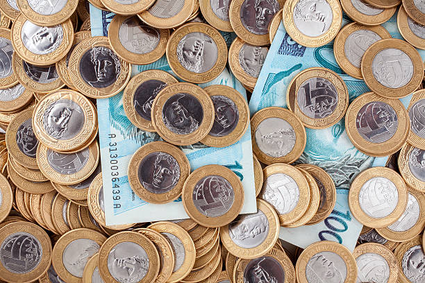Brazilian 1 Real coins and 100 Reais bank notes stock photo