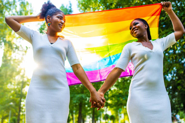 brazilian lesbian couple in white dress spending time together celebrating engagement in summer park outdoor stock photo