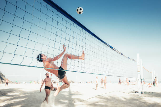 brazilian man jumping for soccerball at volleyball net in Rio stock photo