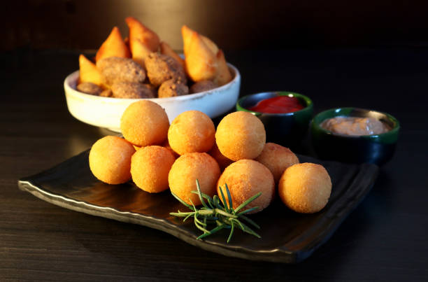 Brazilian snack bolinha de queijo, deep fried balls stuffed with cheese on dark background. Selective focus. stock photo