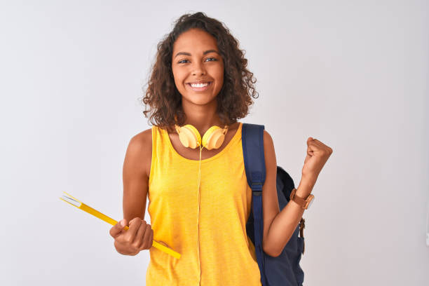 Brazilian student woman wearing backpack holding notebook over isolated white background screaming proud and celebrating victory and success very excited, cheering emotion Brazilian student woman wearing backpack holding notebook over isolated white background screaming proud and celebrating victory and success very excited, cheering emotion brazilian ethnicity stock pictures, royalty-free photos & images