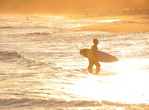 Brazillian surfer walks toward the shore in Rio de Janeiro stock photo