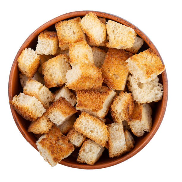 Bread rusks. Fried pieces of bread in a clay bowl isolated on white background. Caesar salad ingredients. Delicious snacks. Top view. stock photo