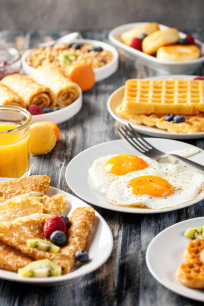 Breakfast - fried eggs, pancakes, crepes, croissants Breakfast - fried eggs, pancakes, crepes, croissants, wafers, a granola on a wooden background. brunch stock pictures, royalty-free photos & images