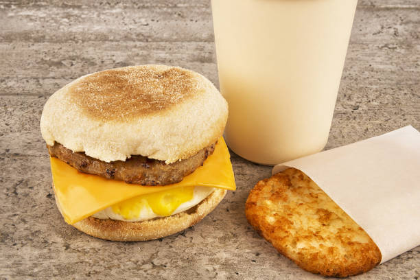 Breakfast sandwich with coffee and hash brown on concrete table Breakfast sandwich with coffee and hash brown on concrete table. English muffin, egg, cheese and sausage. hash brown stock pictures, royalty-free photos & images