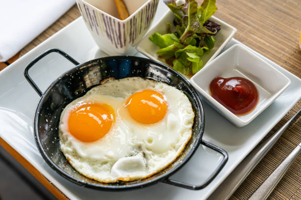 Breakfast - Sunny side up fried eggs with tomato sauce and potato wedges. stock photo