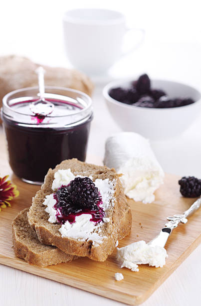 Breakfast with bread, blackberry jam and fresh goat cheese stock photo
