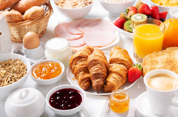 Breakfast with croissants, coffee, juice, meat, jam, cereals and fresh fruits Breakfast with croissants, coffee, juice, meat, jam, cereals and fresh fruits on a wooden table self service photos stock pictures, royalty-free photos & images