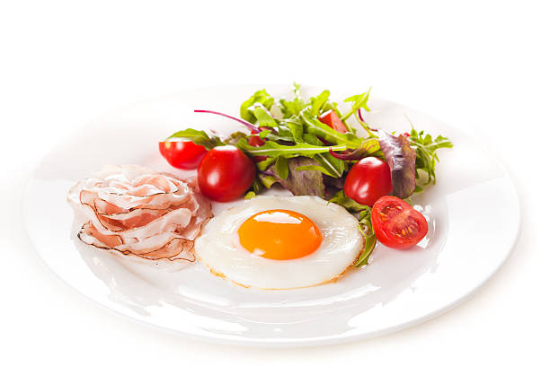 Breakfast with eggs, ham and fresh salad with tomatoes. stock photo