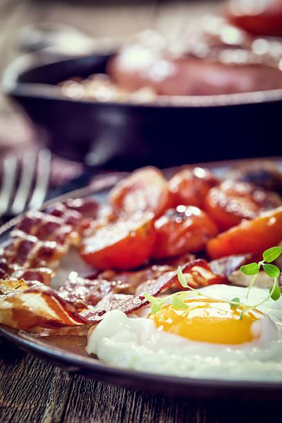 Breakfast with fried eggs, bacon, beans and cherry tomatoes stock photo