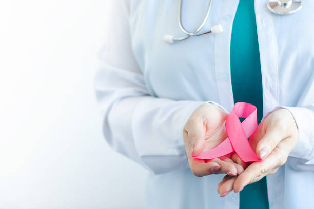 Breast Cancer Awareness Month. Female doctor in medical white uniform holds pink ribbon in her hands. Women's health care stock photo