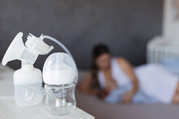 Breast pump attached to a baby bottle Breast pump and baby bottle on the table at nursery increase breast milk stock pictures, royalty-free photos & images