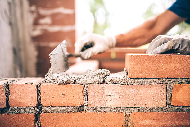 Bricklayer worker installing brick masonry on exterior wall stock photo