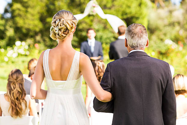 Bride And Father Walking Down The Aisle During Outdoor Wedding stock photo