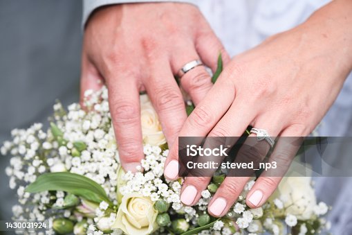 istock Bride and Groom hands over wedding flowers showing their marriage rings 1430031924