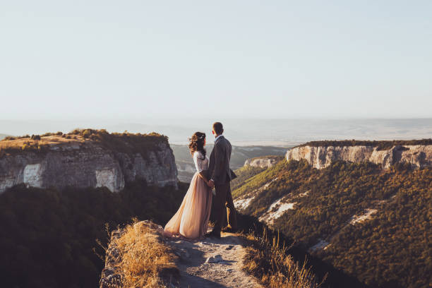 Bride and groom walking in mountains at sunset. Around the stunning scenery with views of the mountains and canyon Mangup stock photo