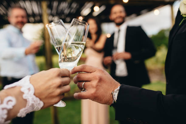 Bride and groom with glasses of champagne Close up of new married couple toasting champagne glasses at wedding party. Bride and groom hands clinking glasses at wedding reception. wedding reception stock pictures, royalty-free photos & images