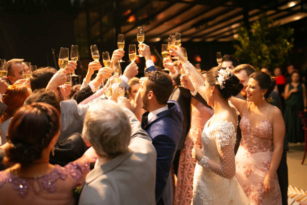 Bride, groom and wedding guests making a toast Bride, groom and wedding guests making a toast wedding reception stock pictures, royalty-free photos & images