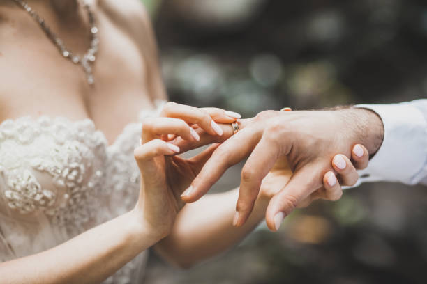 Bride putting ring on groom hand close-up stock photo