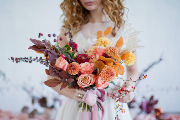 Bride with colorful autumn bouquet Bride holds beautiful autumn bouquet with orange and red flowers and berries. Autumn bouquet with ribbons in bride's hands wedding stock pictures, royalty-free photos & images