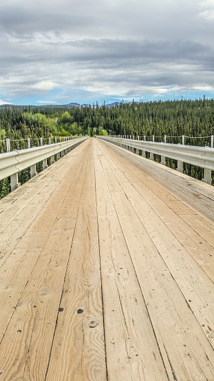 A wooden bridge fades into the distance in Interior Alaska. The Kuskalana Bridge is a great accomplishment in Interior Alaska, spanning across a deep gorge.