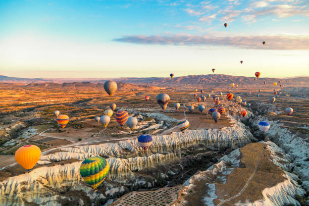 Bright and colourful hot air balloons at sunrise floating along the valleys and mountains in Cappadocia, Turkey stock photo