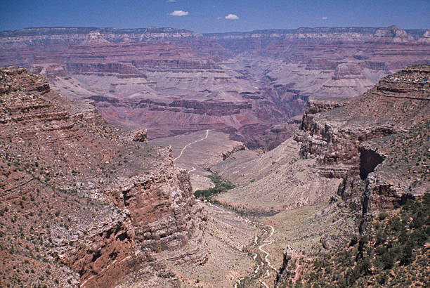 Bright Angel Trail in the Grand Canyon The Grand Canyon is a steep-sided canyon carved by the Colorado River. It is 277 miles long, up to 18 miles wide and attains a depth of over a mile. The canyon and adjacent north and south rims are contained within Grand Canyon National Park, the Kaibab National Forest, Grand Canyon-Parashant National Monument, the Hualapai Indian Reservation, the Havasupai Indian Reservation and the Navajo Nation. In the Grand Canyon the carving of the Colorado River has exposed nearly two billion years of the earth's geological history and created some stunning scenery. This scene of the Bright Angel Trail was photographed from Canyon Village in Grand Canyon National Park, Arizona, USA. jeff goulden scanned film stock pictures, royalty-free photos & images
