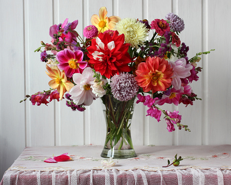 bright autumn bouquet of dahlias and asters on the table near the white wall rustic interior flowers in a glass vase