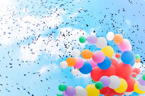Bright balloons and confetti against the sky. Concept of holiday and festive mood.