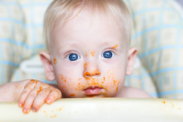 Bright, blue eyed child covered in carrots stock photo