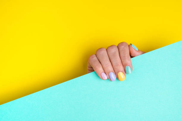 Bright colorful manicure on yellow and mint background. stock photo