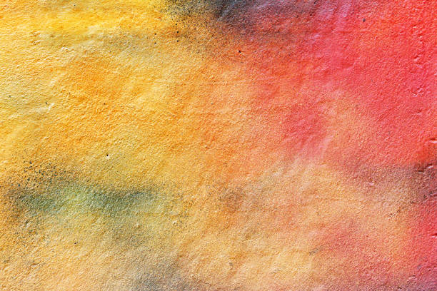 Bright modern texture with red, yellow and orange paint mixed on the wall A bright yellow orange concrete wall randomly spray-painted. Unique bright colorful street background airbrush stock pictures, royalty-free photos & images