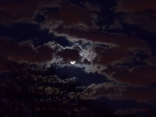 Bright Moon Glowing Behind Clouds stock photo