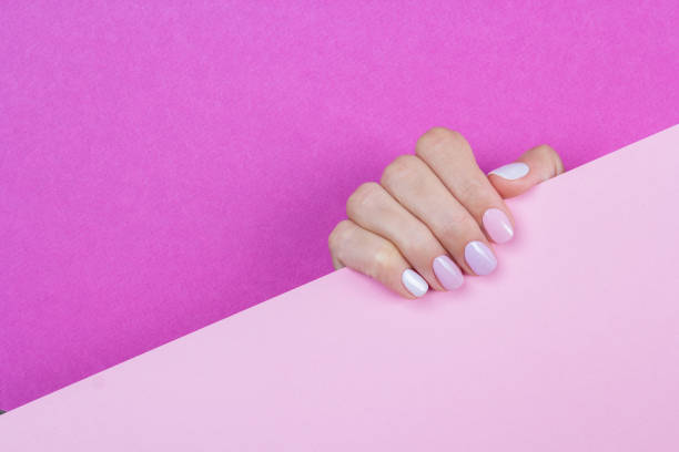Bright purple gel manicure on pink background. stock photo