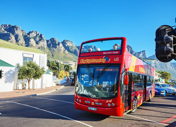 Bright red tourist bus driving into Camps Bay, Cape Town, South Africa stock photo