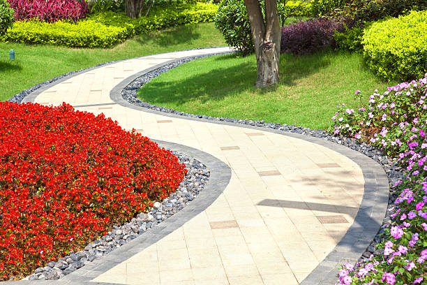 Bright summer garden planted alongside winding tile walkway Beautiful summer garden with a walkway winding its way through garden path stock pictures, royalty-free photos & images