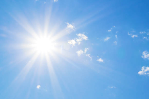 Bright sun with beautiful beams in the sky with clouds Bright sun with beautiful beams in the blue sky with clouds. Space for copy. sun stock pictures, royalty-free photos & images