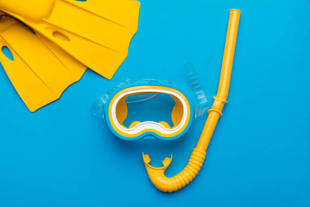 Bright yellow flippers and diving mask on a vibrant backround Bright yellow flippers and diving mask on a vibrant backround aqualung diving equipment photos stock pictures, royalty-free photos & images