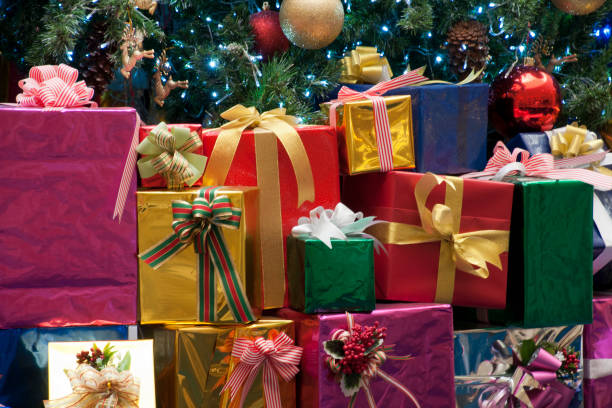Brightly wrapped presents Xmas presents stacked under tree below stock pictures, royalty-free photos & images