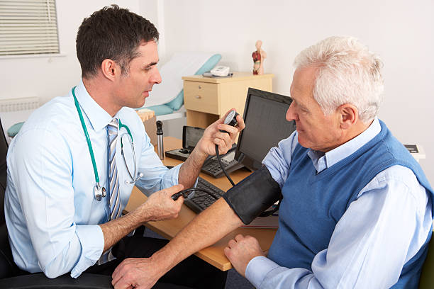 British doctor taking senior man's blood pressure British doctor taking senior man's blood pressure in surgery room having a check up general practitioner stock pictures, royalty-free photos & images