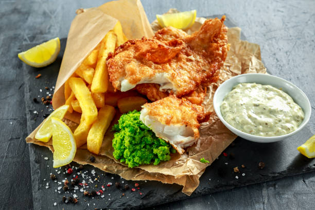 British Traditional Fish and chips with mashed peas, tartar sauce on crumpled paper. British Traditional Fish and chips with mashed peas, tartar sauce on crumpled paper fried fish stock pictures, royalty-free photos & images