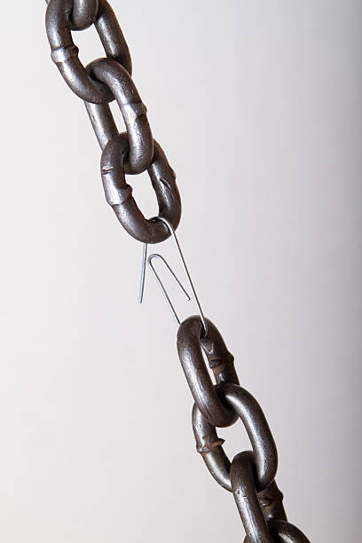 Broken chain link held together by paper clip stock photo