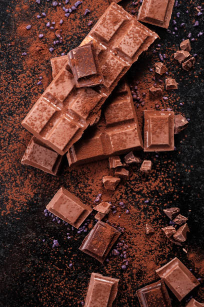 Broken chocolate pieces and cocoa powder on marble. stock photo