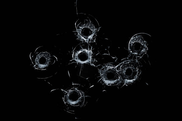 gebroken glas meerdere kogelgaten in glas geïsoleerd op zwart - vuurwapen stockfoto's en -beelden