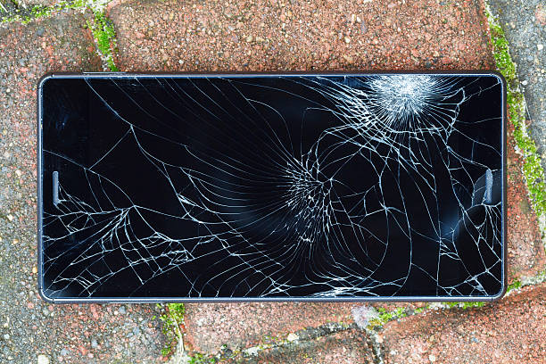 Broken mobile phone lying on pavement stock photo